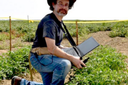 Ari Kornfeld kneeling in the field testing stress detection technology.